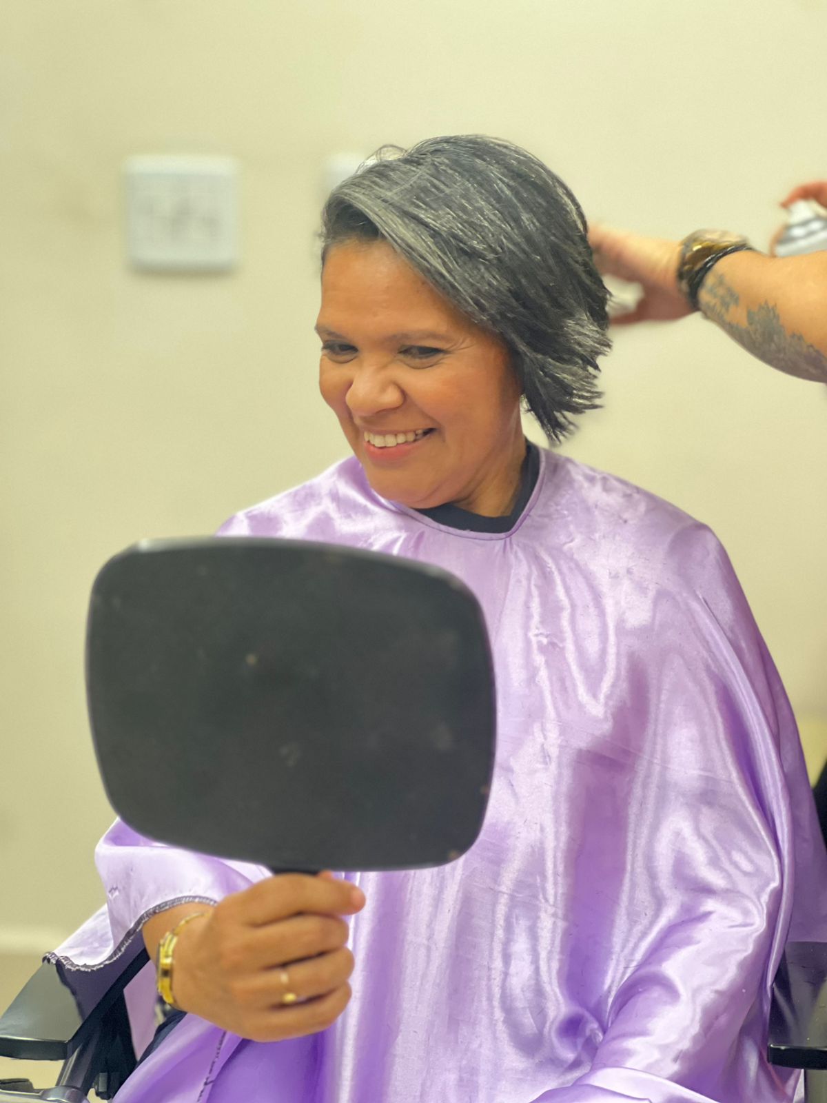 Mulher sorrindo ao se olhar no espelho após cuidado com o cabelo
